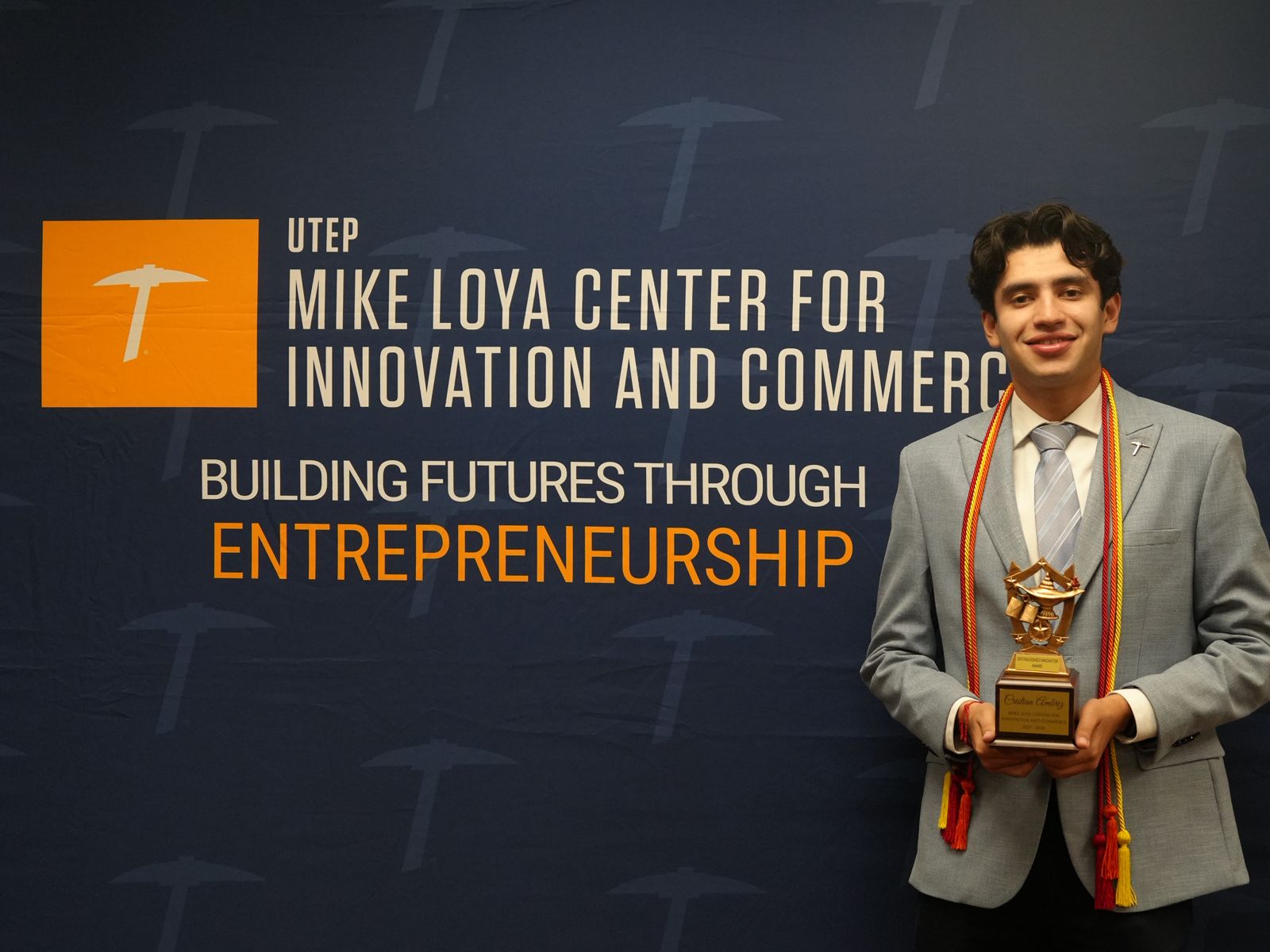 Cristian Ambriz holding the Distinguished Innovator Award at UTEP